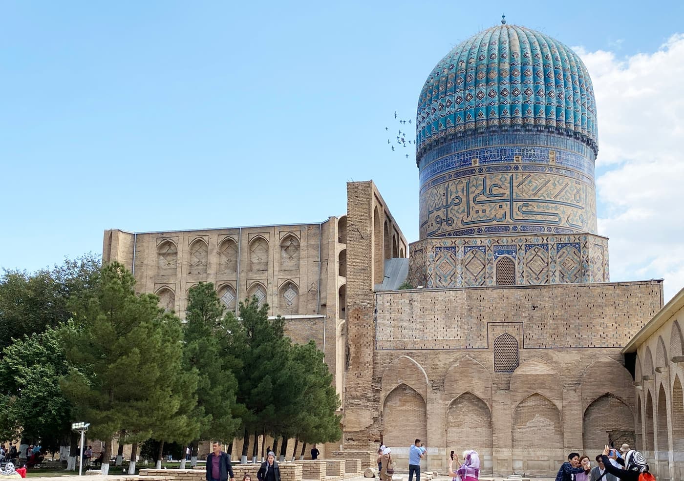 A domed hall of the Bibi-Khanym Mosque rising above the trees of the courtyard